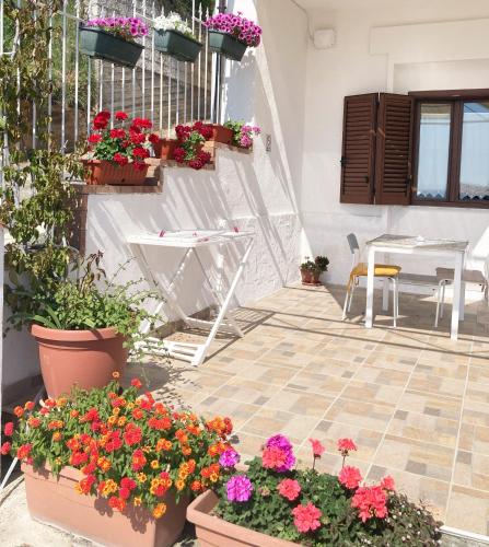 a patio with flowers and a table and chairs at La Meriggia B&B in Pisciotta