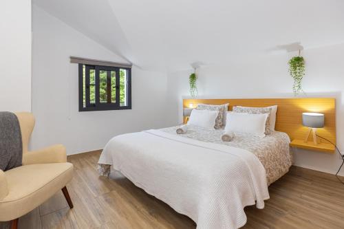 a white bedroom with a bed and a chair at Ilha Natura in Santana