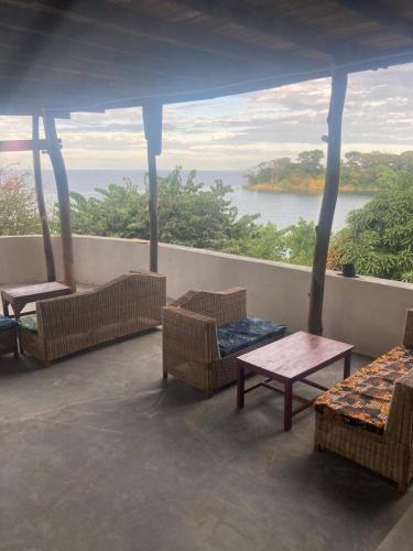 a balcony with chairs and tables and a view of the water at Soul Rebel Lodge & Backpackers in Nkhata Bay