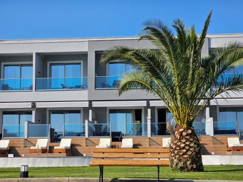 a palm tree in front of a building with a bench at Sea Coast Resort Halkidiki in Yerakiní