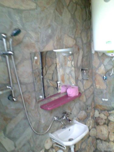 a stone bathroom with a sink and a shower at La Actoru` in Vama Veche
