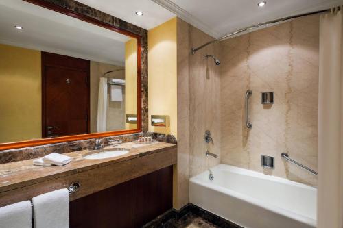 y baño con lavabo, bañera y espejo. en Sheraton Dammam Hotel & Convention Centre en Dammam