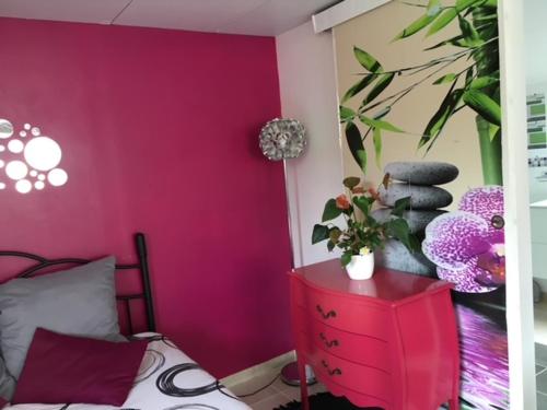 een slaapkamer met een roze muur en een rode dressoir bij Gite des 2 arbres de la sagesse , agréable chalet avec spa privatif in Ardentes