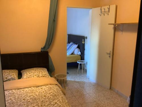 1 Schlafzimmer mit 2 Betten und einer Tür, die in ein Zimmer führt in der Unterkunft L’îlet Songes in Cilaos