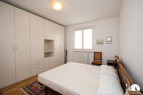 ein weißes Schlafzimmer mit einem Bett und einem Fenster in der Unterkunft Casa della Rocca in Manerba del Garda
