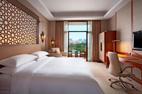 a hotel room with a large bed and a desk at Sheraton Qingyuan Lion Lake Resort in Qingyuan