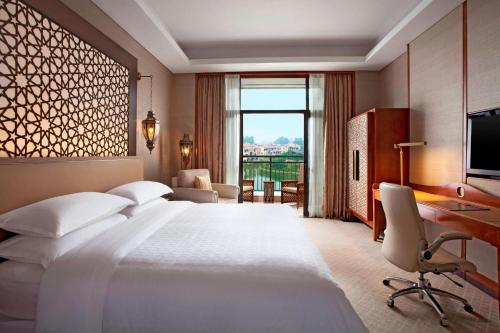 una camera d'albergo con un grande letto e una scrivania di Sheraton Qingyuan Lion Lake Resort a Qingyuan