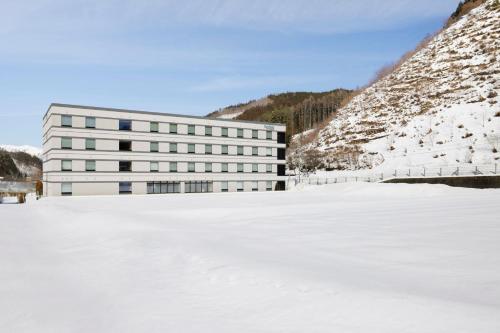 a building in the snow next to a snow covered field at Fairfield by Marriott Gifu Takayama Shirakawa Go in Takayama