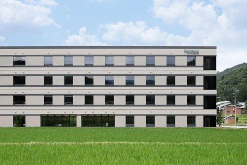 a large white building with a field in front of it at Fairfield by Marriott Gifu Takayama Shirakawa Go in Takayama