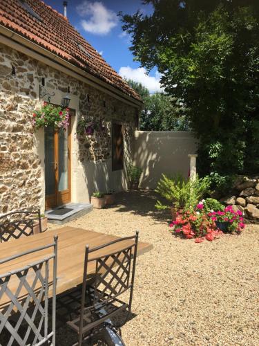 a patio with a wooden table and chairs in front of a house at Gites du Manoir in Runan
