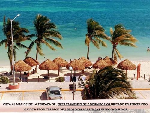 a beach with straw umbrellas and palm trees and the ocean at Apartamentos Magali in Cancún