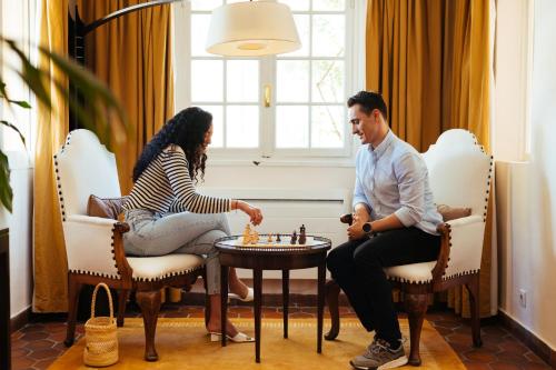 een man en een vrouw die schaken in een kamer bij Auberge du Redier in Colomars