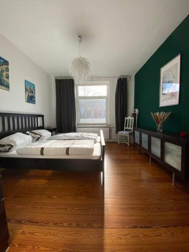 1 dormitorio con cama y pared verde en Altbauwohnung mit viel Charme in zentraler Lage en Kiel
