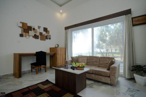 a living room with a couch and a large window at Reunion Ocean Manor - Beach House in Udupi
