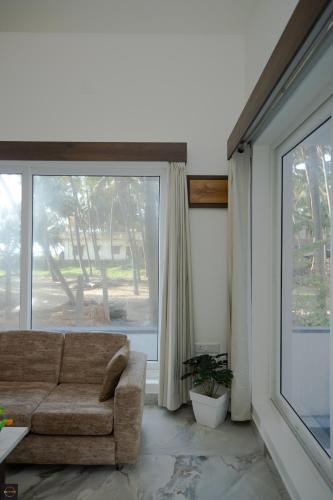 a living room with a couch and a large window at Reunion Ocean Manor - Beach House in Udupi