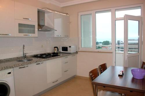 a kitchen with white cabinets and a table with a dining room at Star apartments in Trabzon