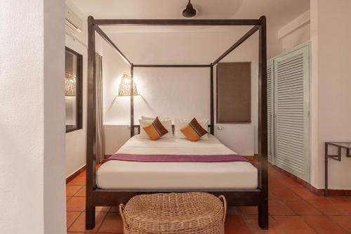 um quarto com uma cama de dossel e uma cadeira de vime em Maison 557 em Siem Reap