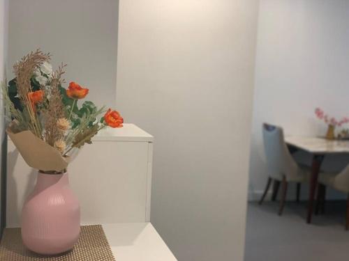 a pink vase with orange flowers sitting on a table at CBD Spacious Two Bedrooms Apartment in Melbourne