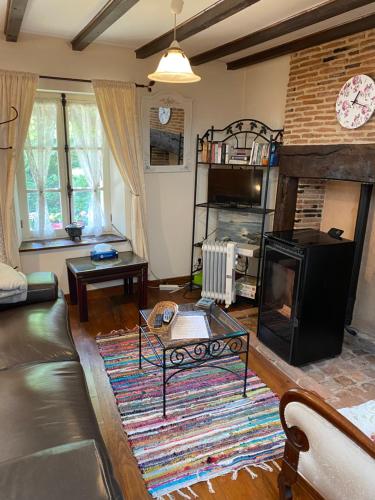 un salon avec un canapé et une cheminée dans l'établissement Red Gate Cottage, à Saulgond