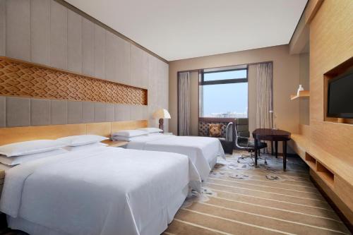 a hotel room with two beds and a flat screen tv at Sheraton Xi'an North City Hotel in Xi'an