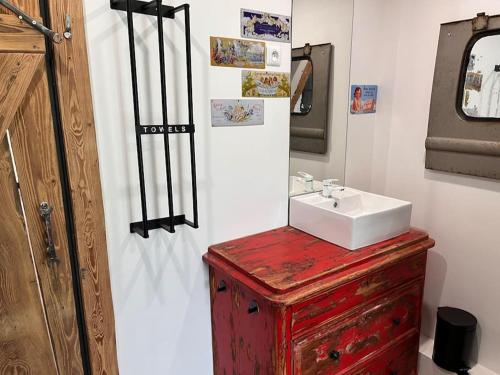 a bathroom with a white sink and a red wooden cabinet at Le grenier a foin in Breitenbach-Haut-Rhin