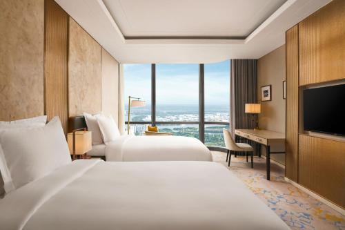a hotel room with two beds and a desk at Vinpearl Landmark 81, Autograph Collection in Ho Chi Minh City