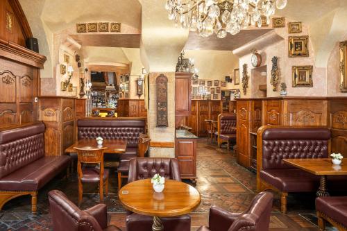 a restaurant with tables and chairs and a chandelier at Hotel U Prince Prague by BHG in Prague
