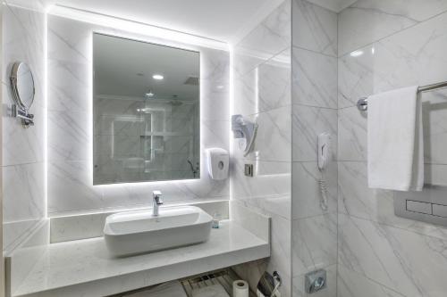 Baño blanco con lavabo y espejo en Alba Resort Hotel, en Side