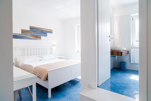 a white bedroom with a bed and a desk at Un Posto al Mare in Santa Maria di Castellabate