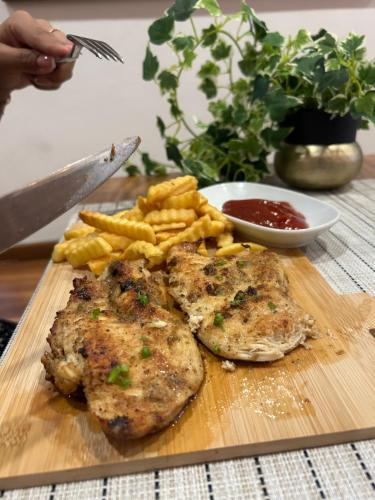 a wooden cutting board with meat and french fries at The Cabin Hotel in Accra