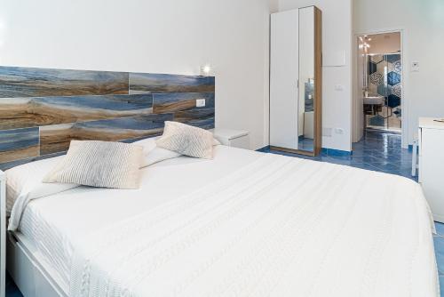 a bedroom with a white bed with a wooden headboard at Un Posto al Mare in Santa Maria di Castellabate
