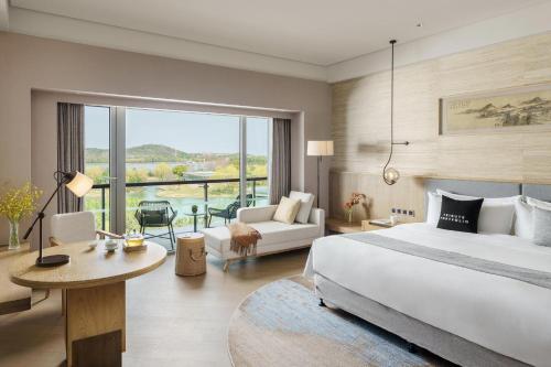 a bedroom with a large bed and a living room at The Yuluxe Sheshan, Shanghai, A Tribute Portfolio Hotel in Songjiang