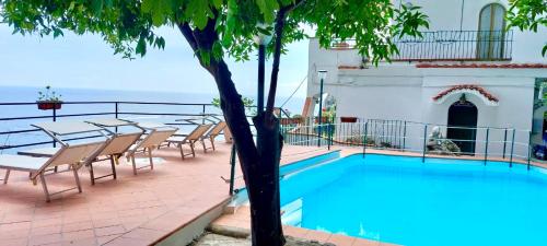 einem Pool mit Stühlen und einem Tisch neben einem Gebäude in der Unterkunft Villa Carmela in Conca dei Marini