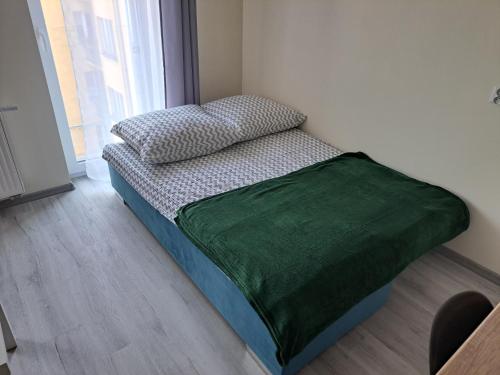 a bed with a green comforter in a room at 44 Piotrkowska Street in Łódź