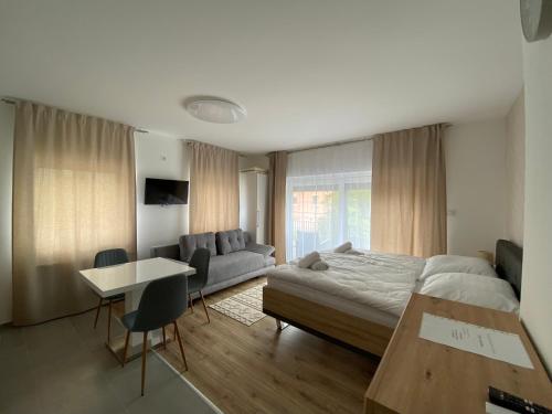 ein Schlafzimmer mit einem Bett, einem Sofa und einem Tisch in der Unterkunft Cédrus Apartman in Balatonfüred