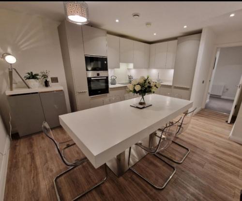 a kitchen with a white table with flowers on it at Modern apartment, sleeps 6, Belfast city centre in Belfast