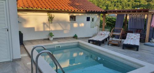 a swimming pool with two chairs next to a house at Studio-Apartman-Diana in Brseč