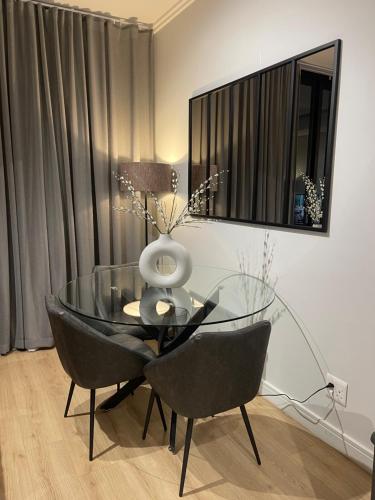 a glass table with two chairs and a vase on it at Exec Oasis @Ellipse in Midrand