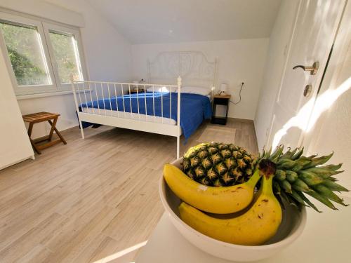 Zimmer mit einer Schale Ananas und einem Bett in der Unterkunft Apartments Rudelinka in Karlobag