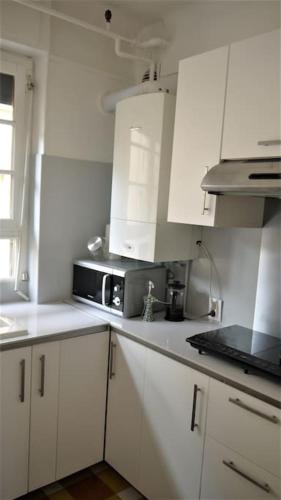 une cuisine avec des armoires blanches et un micro-ondes dans l'établissement Appartement familial 3 chambres centre proche Lot, à Cahors