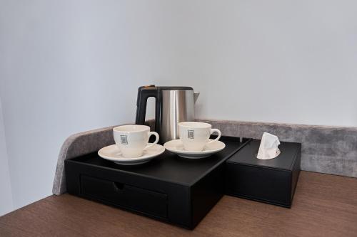 two coffee cups and a coffee maker on a black cabinet at WHITE HILLS HOTEL spa&sport in Uzhhorod