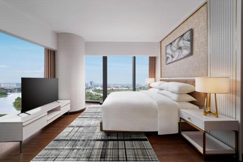 a bedroom with a white bed and a large window at Sheraton Hai Phong in Hai Phong