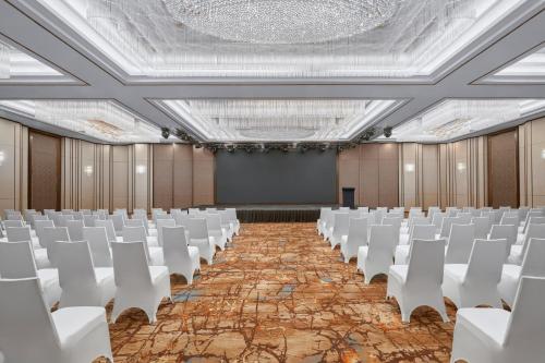an empty room with white chairs and a projection screen at Sheraton Hai Phong in Hai Phong