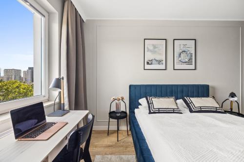 a bedroom with a bed and a desk with a laptop at Marina Primore - Hampton Apartments in Gdańsk