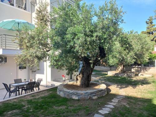 a tree in front of a building with a table and chairs at Sandra's luxury stay in Akti Salonikiou