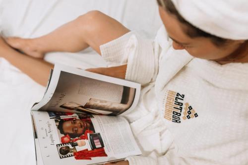 a woman laying in bed reading a magazine at ZLATIBOR HIGHLAND in Zlatibor