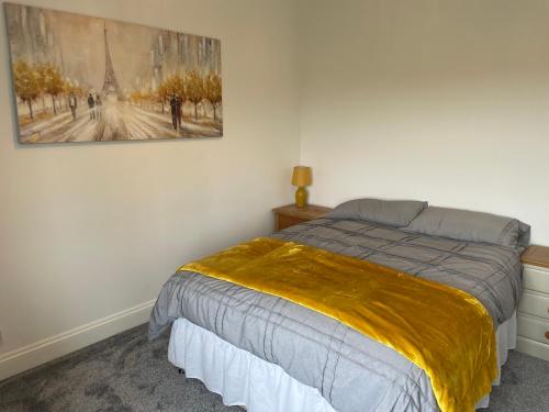 1 dormitorio con 1 cama y una pintura en la pared en Fern Cottage, en Thorpe le Soken