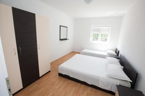 a white bedroom with a bed and a window at Apartment Stipan in Bibinje