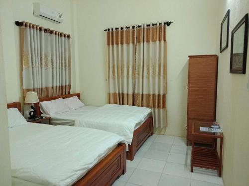 a bedroom with two beds and a dresser and curtains at Quy Phuong - Homestay in Tân Hiệp
