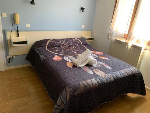 a stuffed animal laying on a bed in a bedroom at Hôtel Le Bel Air in Lanuéjols